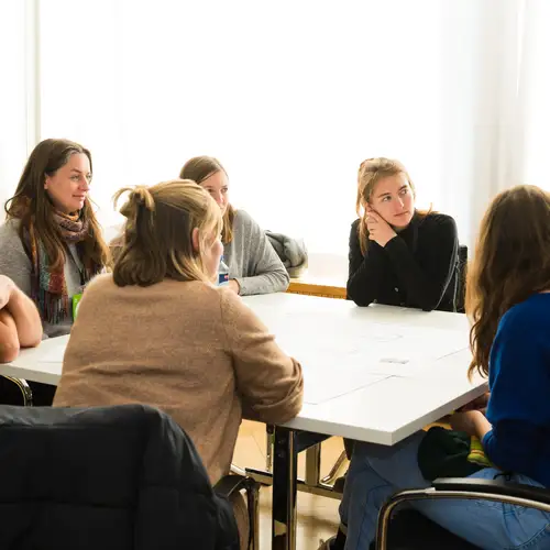 Mehrere Menschen sitzen um einen Tisch herum und diskutieren
