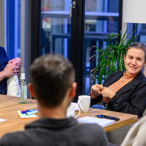 Vier Personen sitzen im Gespräch um Tisch
